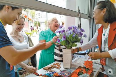 在莫斯科的北京地坛庙会上，北京民间工艺美术大师、绢花工艺传承人徐汶静(右一)带来的传统绢花颇受欢迎。本报记者 吴 焰摄